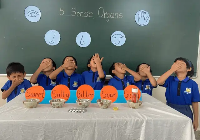 a group of children of class Upper K.G of Ashish Preschool covering their eyes and covering their mouth during sense organ activity